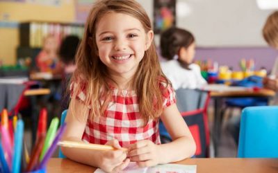 Portrait Of Smiling Female Elementary School Pupil Working At Desk